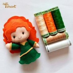 an orange haired doll next to spools of thread and a roll of thread