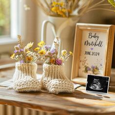 baby booties with flowers in them sitting on a table next to a photo frame