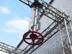 a red object hanging from the side of a metal structure with blue sky in the background