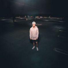 a man standing in the middle of an empty parking lot at night with his hands on his hips