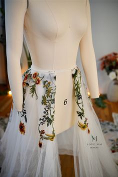 there is a white dress with flowers on the bottom and side, but it has an attached belt