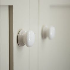 two white cupboards with knobs and handles on them