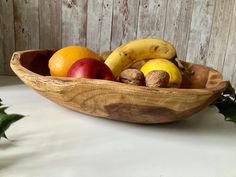 a wooden bowl filled with fruit on top of a table