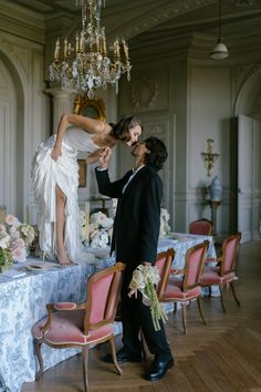 a bride and groom standing in front of a table with chandelier hanging from the ceiling