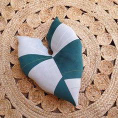 a green and white heart shaped pillow sitting on top of a wicker place mat