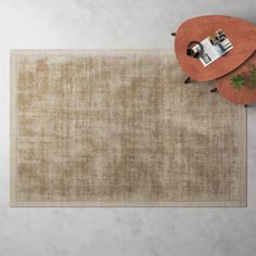 an overhead view of a beige rug on the floor next to a coffee table and chair