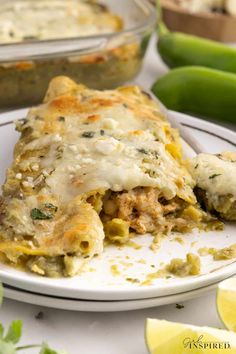 a white plate topped with lasagna covered in cheese and sauce next to green beans