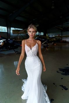 a woman in a white wedding dress is posing for the camera with an airplane behind her