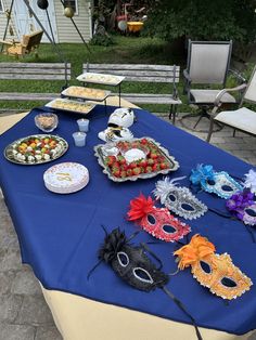 a blue table topped with lots of plates and maskes on top of it's sides