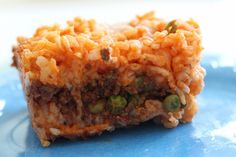 a piece of food sitting on top of a blue plate covered in rice and peas