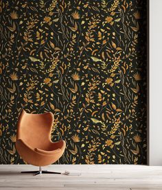 an orange chair sitting in front of a black wallpaper with yellow and green flowers