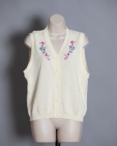 Cute womens 70s 80s button front knit vest. Cream color with pretty flower and butterfly design. S.G. SPORT Collection size - Medium vintage pre-owned Retro V-neck Vest For Spring, Vintage V-neck Vest For Spring, Retro V-neck Spring Vest, Retro Spring Vest, Spring V-neck Retro Vest, Spring Vintage Vest, Retro Cotton Sweater Vest For Spring, Vintage V-neck Sweater Vest For Spring, Vintage Sleeveless Sweater Vest For Spring