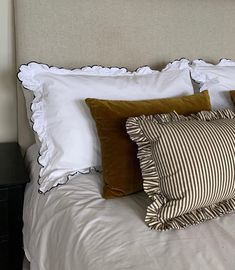 a bed with white sheets and brown pillows