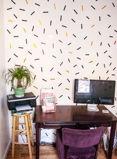 a desk with a computer on it in front of a white wall decorated with sprinkles