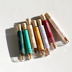 five different colored pens lined up in a row on a white surface with gold caps