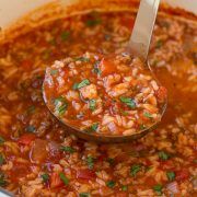 a ladle full of soup is being held by a spoon