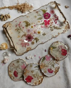 three plates with flowers on them sitting on a white table cloth next to other items