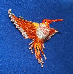 a beaded bird brooch sitting on top of a blue cloth