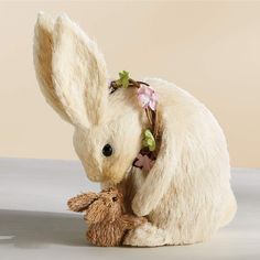 a stuffed rabbit with a flower wreath on its head is sitting next to a teddy bear