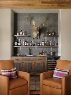 two leather chairs sitting in front of a bar with deer heads on the wall behind them