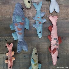 several stuffed fish are arranged on a wooden surface, including one blue and one pink