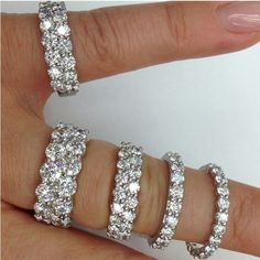 a woman's hand with five diamond rings on her left and the middle finger