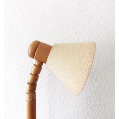 a wooden table lamp with a beige shade on it's arm, against a white wall