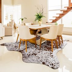 a dining room table with chairs and a cow hide rug on the floor in front of it