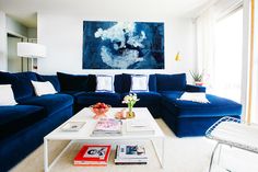 a living room filled with blue couches and white tables