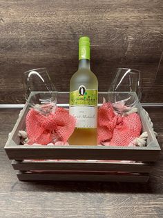 a bottle of wine and two glasses in a tray with seashells on it