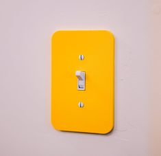 a yellow light switch sitting on top of a white wall