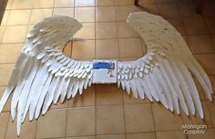 an angel wing made out of cardboard on the floor