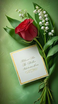 a red rose sitting on top of a card next to some green leaves and flowers