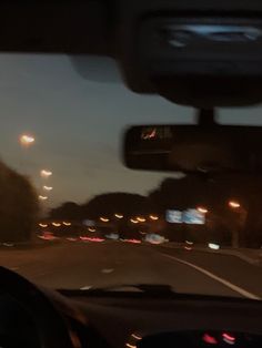 the view from inside a car at night with street lights and trees in the background