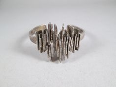 "A modernist brutalist silver cuff bracelet, possibly by Danish jewelry maker Poul E. Boesen. I could find very little of Boesen's work online, only a brooch marked P.E.B.  This wondrous piece most likely dates from the 1960s, is stamped 830s and scratch tests as silver weighing 74.7 grams.  The cuff features jagged brutalist panels vertically wedged and soldered together for dramatic effect, with a tapered band.  I haven't polished it and will leave that decision to the new owner.  It will make a fine addition to any serious mid-century modernist jewelry collection. Inner circumference 7\".  Width of panels 1 3/8\"" Chunky Silver Bracelet, Silver Wrap Bracelet, Jewelry Ads, Modernist Jewelry, Silver Cuff Bracelet, Metal Bracelets, Jewelry Maker, Silver Cuff, Silver Bangles