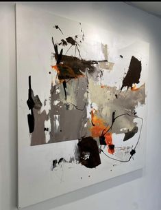 an abstract painting hanging on the wall in a white walled room with black and orange accents