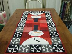 a table runner with snowmen on it sitting on top of a wooden dining room table