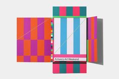 an open book with colorful stripes on the cover and inside is a diagonal strip of colored paper