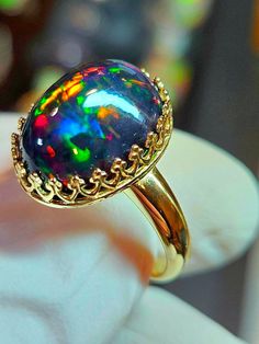 Black fire opal, this one is a beauty and was a challenge to photographed well. Very colorful and bright with a lovely horizontal honeycomb pattern. stone is 12x16mm and 8.9cts.  Mounted in a 14k solid gold heavy crown style bezel ring. The prongs will be closed when the ring size is determined. Opal And Black Diamond Ring, Black Opal Jewelry Opal Auctions, Black Opal Ring Opal Auctions, Multicolor Opal Round Ring, Black Cabochon Opal Ring, Multicolor Opal Gemstone Ring, Multicolor Opal Ring, Fire Opal Ring Engagement, Energy Stones Crystal Healing