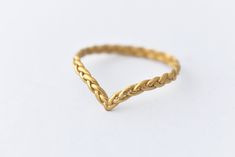 a gold ring that is shaped like a chevron knot, on a white background