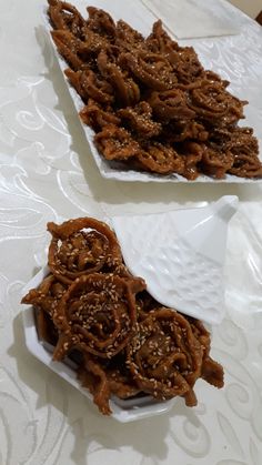 two white dishes filled with food sitting on top of a table next to each other