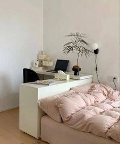 a bed sitting under a window next to a white desk with a laptop on it