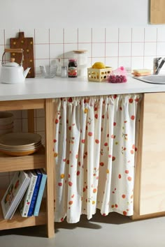 the kitchen counter is covered with curtains and dishes