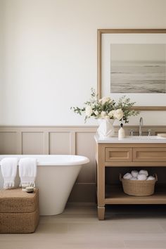 a white bath tub sitting next to a sink under a framed picture on the wall