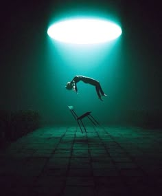 a person diving into the water from a chair in front of a light that is green