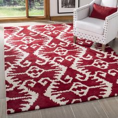 a red and white area rug in a living room with a chair, window and pictures on the wall