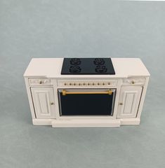 a white toy stove with black burners and gold trim