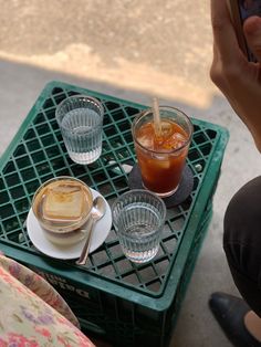 a person sitting at a table with two cups of coffee and a cell phone in front of them