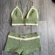 two pieces of green knitted clothing sitting on top of a wooden floor