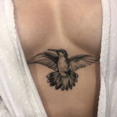 a woman's chest with a bird tattoo on it